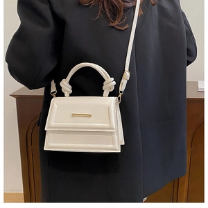 Detailed shot of cream PU leather handbag featuring unique rope knot handle and gold buckle