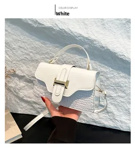 Close-up of white crossbody bag featuring crocodile texture and golden H-shaped clasp