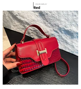 Detail of red crossbody bag featuring gold H-lock and crocodile pattern leather texture