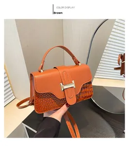 Detail of brown faux crocodile leather texture and gold lock on women shoulder bag