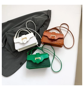 Detailed close-up of small crossbody bags with crocodile texture and gold hardware