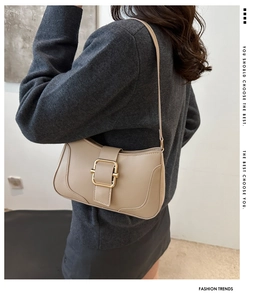 Chic beige underarm bag with gold buckle shown on a model for scale and style