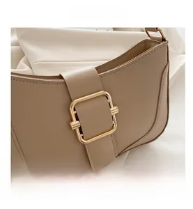 Close-up of golden square buckle and fine stitching on beige minimalist underarm bag