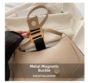 Detailed view of golden magnetic buckle on minimalist beige underarm bag showing closure