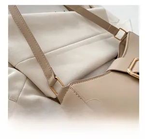 Macro shot of pale gold metal buckle and neat stitching on beige leather handbag