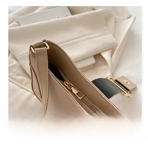 Detail of smooth gold metal zipper on a minimalist beige faux leather underarm bag