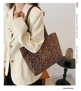 Detailed view of leopard print canvas tote bag carried by model in beige corduroy suit