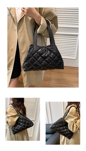 Macro detail of the glossy black quilted puffer tote bag with large diamond stitch patterns