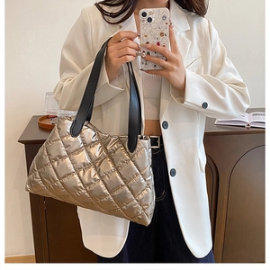 Detailed close-up of champagne gold quilted tote bag with metallic finish and black handles