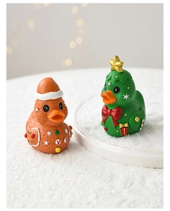 Close-up of resin gingerbread and Christmas tree ducks on snowy desktop background