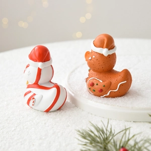 Christmas gingerbread and white resin ducks with Santa hats on snowy festive background
