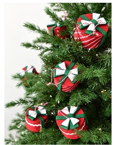 Dettaglio di ornamenti natalizi in feltro rosso e verde appesi a un albero di pino