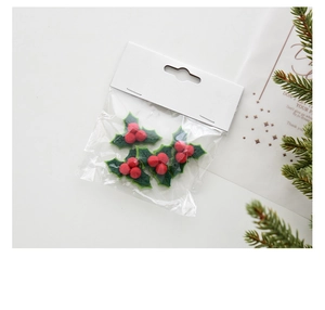Close-up of 4-piece felt holly leaf and red berry Christmas tree ornaments in packaging