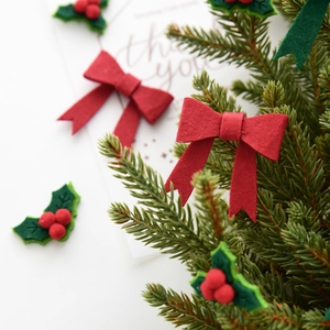 Christmas bow DIY decoration with red felt and holly leaves on green pine branches