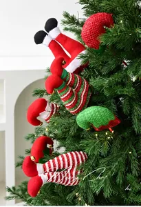 Close-up of festive Christmas elf legs and sequined hat ornaments on a green tree