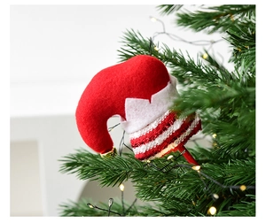 Detail of red felt elf hat ornament with gold bell on a Christmas tree branch