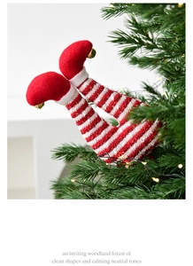 Detailed view of red and white striped Christmas elf legs with gold bells on a Christmas tree