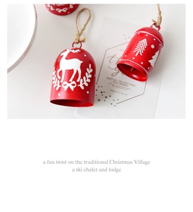 Close-up of red metal Christmas bells with white reindeer and snowflake prints