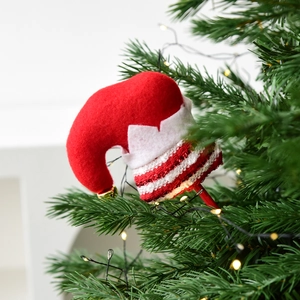 Christmas elf hat decoration with red stripes and golden bell on a green Xmas tree