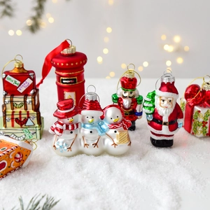 Set of unique painted glass Christmas ornaments including santa and snowmen on snow surface