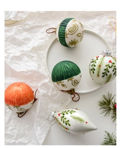 Detail of hand-painted cream glass Christmas ornaments with green stripes and red berries