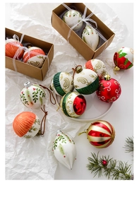 Detailed view of hand-painted Christmas glass ornaments with festive berry motifs in a gift box