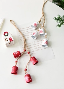 Detail of red and white Christmas bell ornaments on rustic rope with snowflake patterns