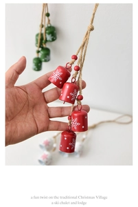 Close-up of red metal Christmas bells with white snowflakes on rustic hemp rope