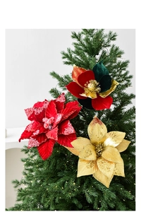 Détail de fleurs de Noël en velours rouge et or sur un sapin avec éclairage festif