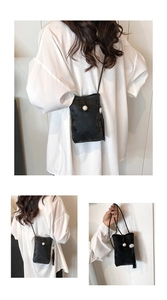 Detail of black crossbody phone bag with satin texture, pearl buckle and long tassel
