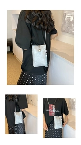 Detail of silver metallic phone crossbody bag with pearl buckle and long fringe tassel