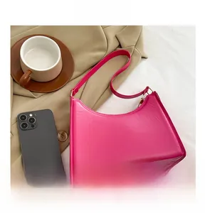 Flat lay detail of a magenta crescent shoulder bag with strap on a white fabric background