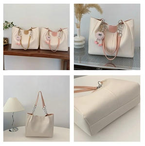 Detail of off-white tote bag featuring chain straps and cute pink plush monster charm