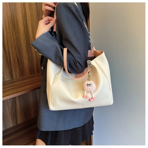 Commuter tote bag featuring off-white body with pink leather straps and plush charm detail