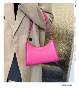 Magenta minimalist baguette bag with gold hardware worn on shoulder with tan blazer