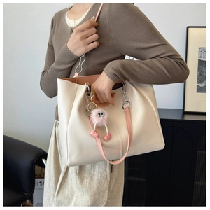 Detail of cream tote bag with pink straps, stitching, silver chain and plush charm