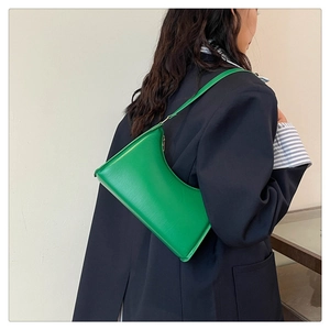 Bright green minimalist faux leather baguette bag worn by a model in black blazer