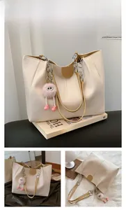 Detail view of khaki tote bag with plush charm and silver chain strap details