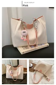 Detail of cream tote bag featuring pink straps, metallic chains and plush charm