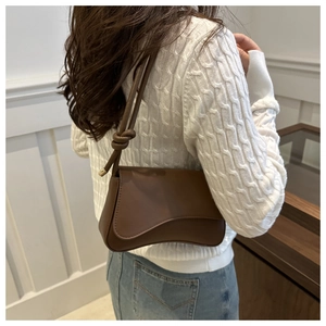 Sac sous le bras en cuir marron avec bandoulière nouée et base incurvée sur modèle