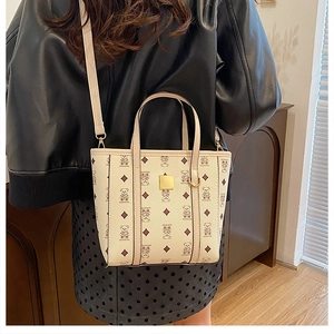 Détail du sac seau en similicuir crème avec imprimé ours et plaque dorée porté par un modèle