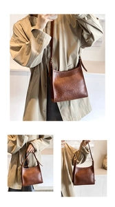 Detail of dark brown vintage leather tote bag showing adjustable strap and oily texture