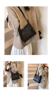 Detail view of black tote bag with litchi texture and adjustable shoulder strap buckle