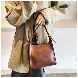 Detail of vintage brown leather handbag with adjustable strap and embossed fashion text