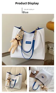 Detail view of large white tote bag with blue trim and cute plush bear accessory