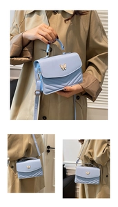 Detail showing baby blue quilted crossbody bag with gold butterfly clasp on beige trench coat