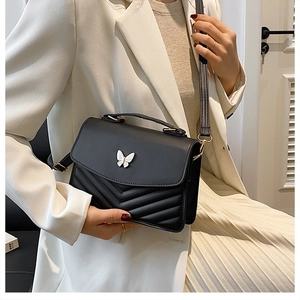 Détail du sac matelassé noir avec fermoir papillon blanc et coutures en forme de V