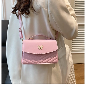 Détail du sac bandoulière rose montrant le fermoir papillon doré et le cuir matelassé