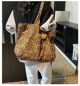 Leopard print tote bag with brown plush bear charm shown in use for size perspective