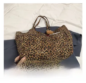Detail showing leopard print canvas tote bag with front pocket and plush bear charm